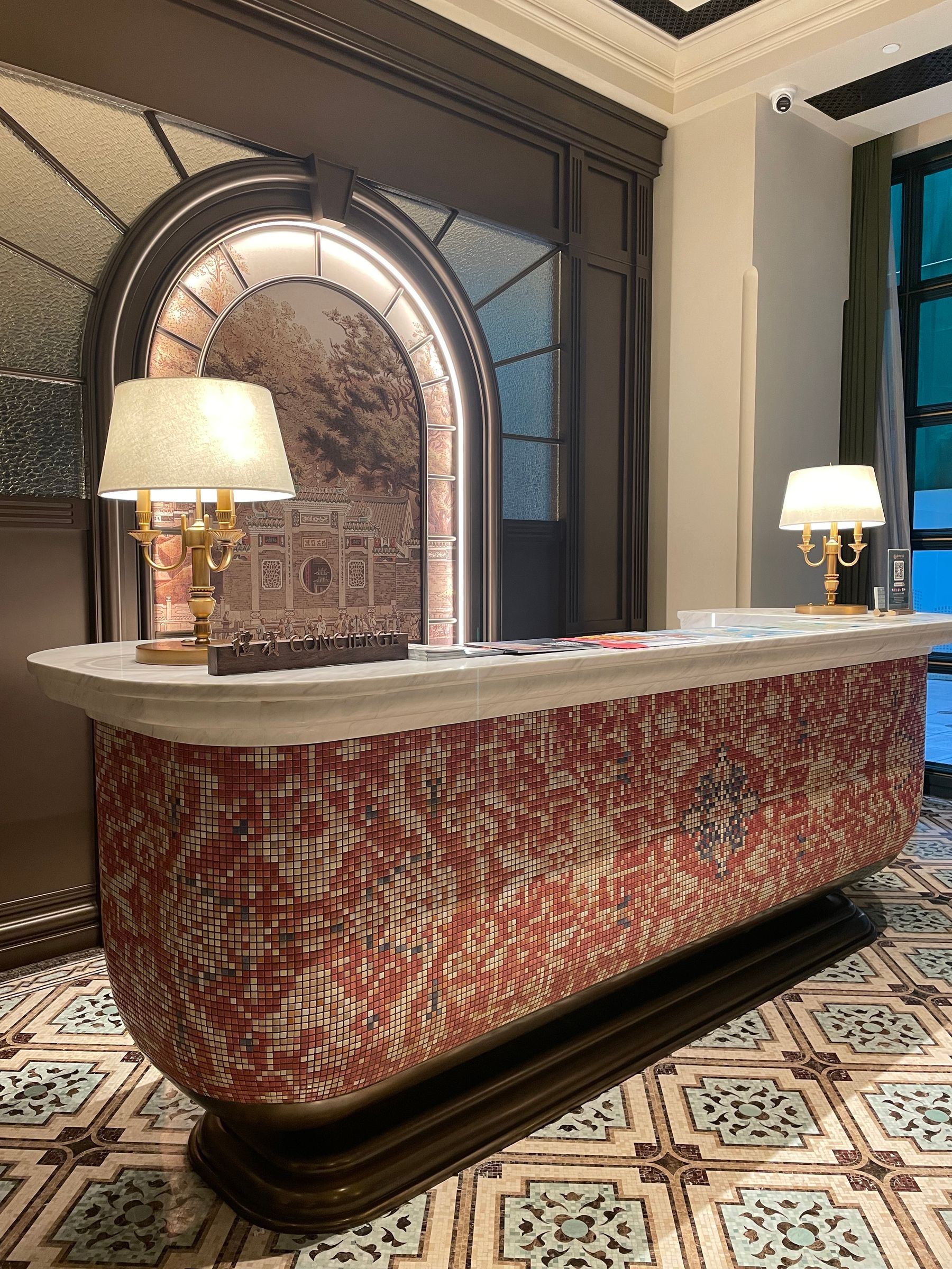 Illustrative concierge desk with mosaic tilework and brass lamps, not the actual property